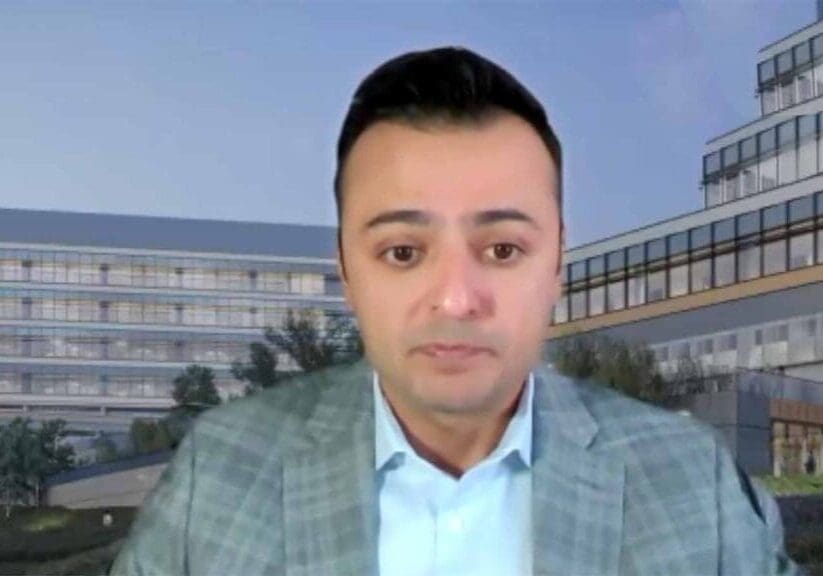 A man in a suit and tie standing next to a building.